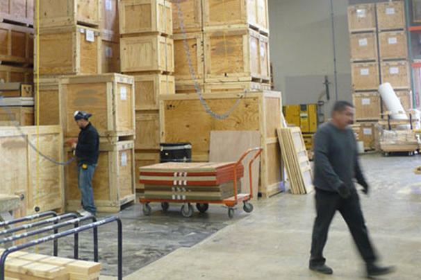 men working in wood shop with crates stacked in background